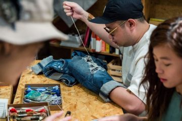 This picture taken on September 9, 2018 shows a participant at a "Fashion Clinic" workshop mending his old jeans. - Despite Hong Kong's reputation for rampant consumerism, a nascent movement against fast fashion is taking root in the city, with clothes-mending workshops and pop-up swaps growing in popularity, and designers parading recycled fabrics on the catwalk. (Photo by Isaac LAWRENCE / AFP) / TO GO WITH HongKong-fashion-environment-textile-lifestyle, FEATURE by Yan ZHAO (Photo credit should read ISAAC LAWRENCE/AFP/Getty Images)